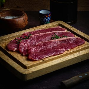 High-quality beef slices garnished with rosemary on a wooden board, perfect for culinary photography.